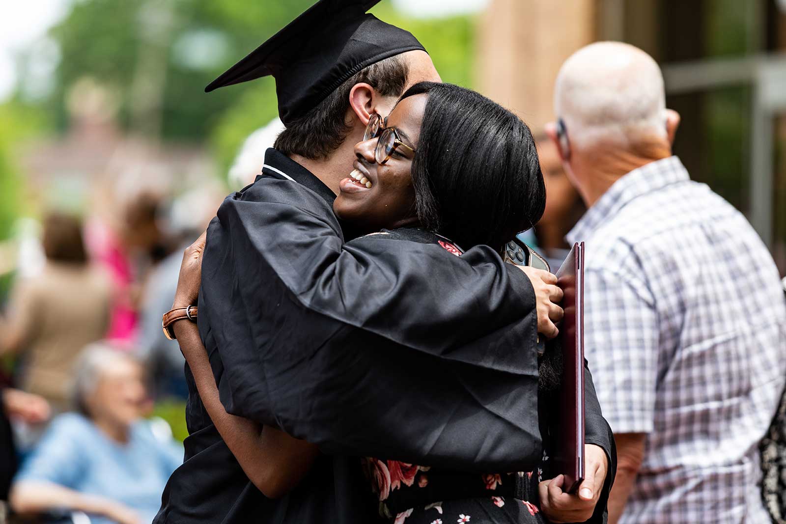 students hugging at commencement outside