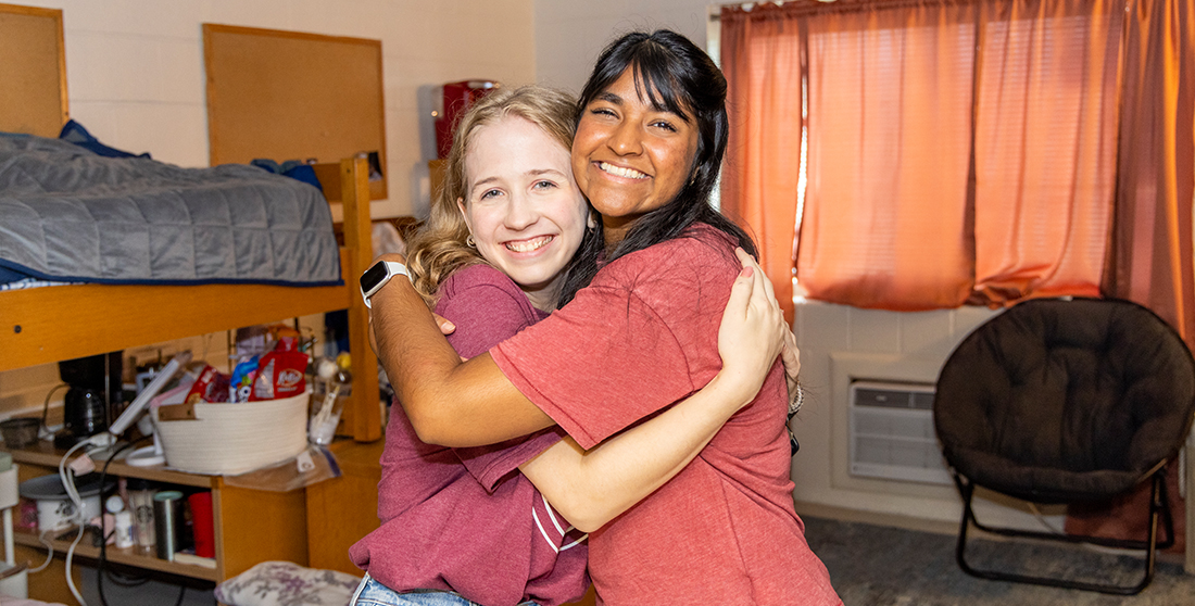 two female students hugging in new dorm room