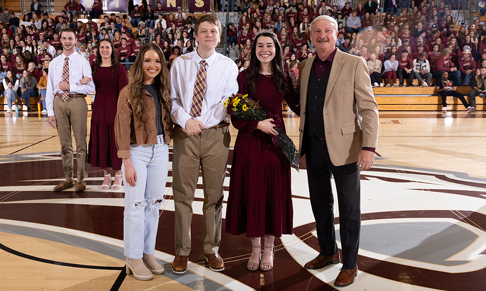 The 2022 homecoming queen, Anniston Butler (left), assists President David R. Shannon (right) in crowning Elijah Brewer and Julie Gann as the 2023 homecoming king and queen.