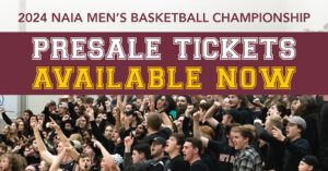 A large excited crowd at a basketball game, with banners reading 2024 NAIA Men’s Basketball Championship and Presale Tickets Available Now in bold white and yellow letters.