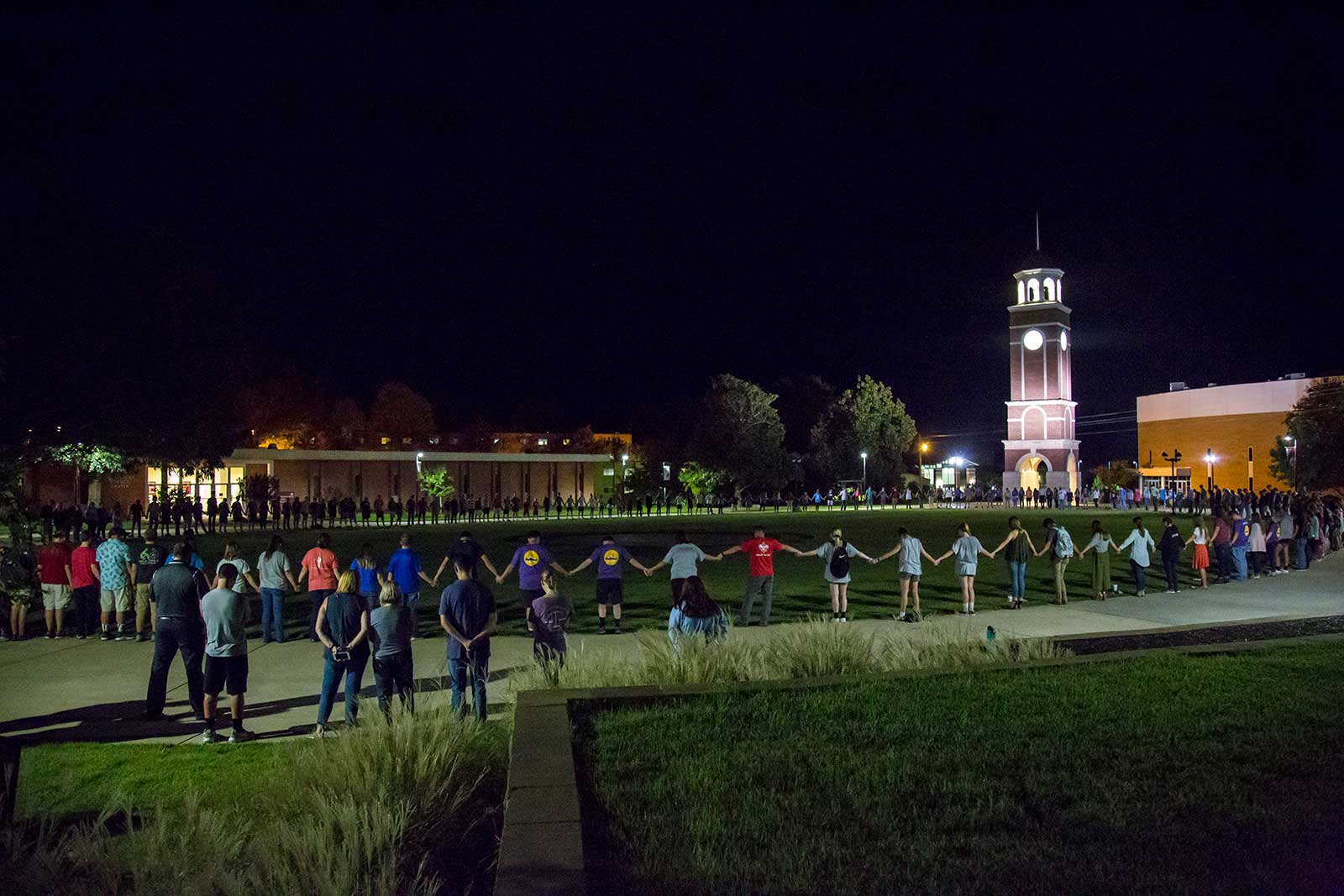 new - large student prayer around clock tower at night