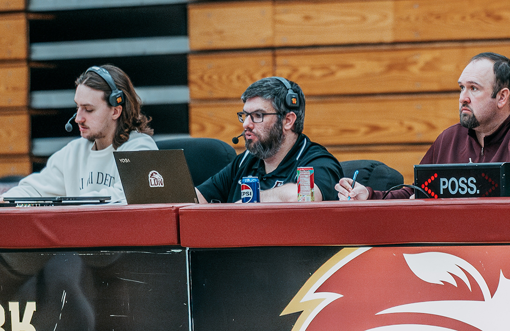 A basketball tournament with Lions sticker on one of the commentators, showing the Athletics side of FHU's Athletic website voted 5th Best in the NAIA