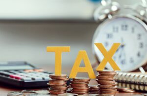 the letters T A X standing on piles of pennies on a desk