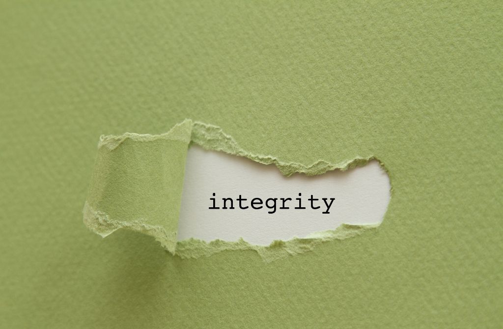 Green paper is pealed back to reveal the word integrity