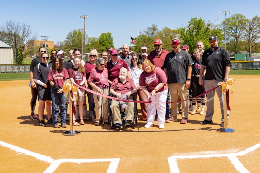 Members of the Tucker and Black families join FHU softball players and coaches to cut the ribbon for the newly named Rayla Tucker Black Field.