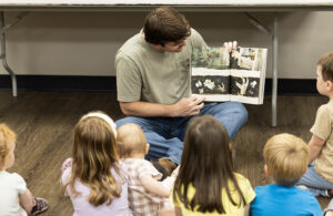 A college student reads to a group of elementary students.