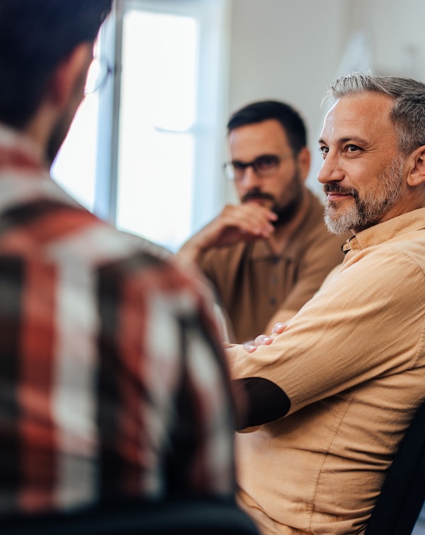 Three men gathered together, conversing seriously.