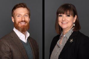 Side-by-side portraits of a bearded man in a brown blazer and a woman with brown hair in a black blazer and striped shirt, both smiling against a plain dark background.