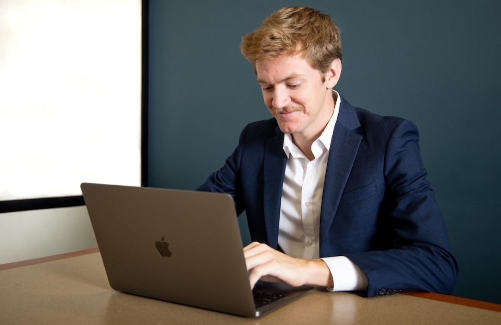 A student sits at a desk and works on his laptop
