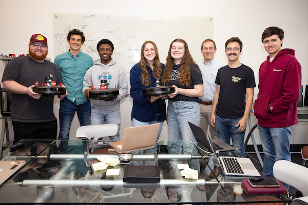 AI for Robotics class members (l to r) Dallas Yarnell, Sean Janiec, Lou Joseph, Allison Walker, Brigitte Turner, Dr. Ben Clark, Bryce Greene and Addison Adcock pose with their robotics after hide and seek game May 4, 2023.