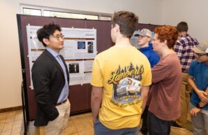 A group of students look at a presentation from another student at a scholar's day event