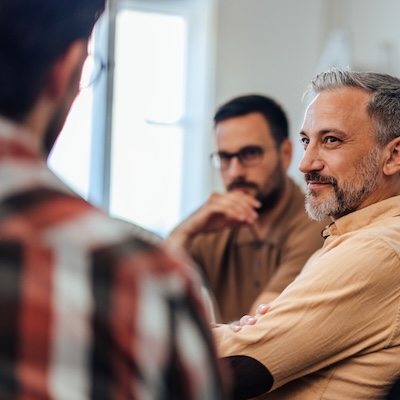 Three men gathered together, conversing seriously.