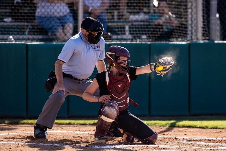 a catcher on the softball team receives the pitch
