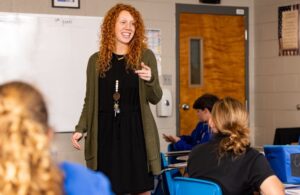 A woman stands in front of her class and teaches a lesson