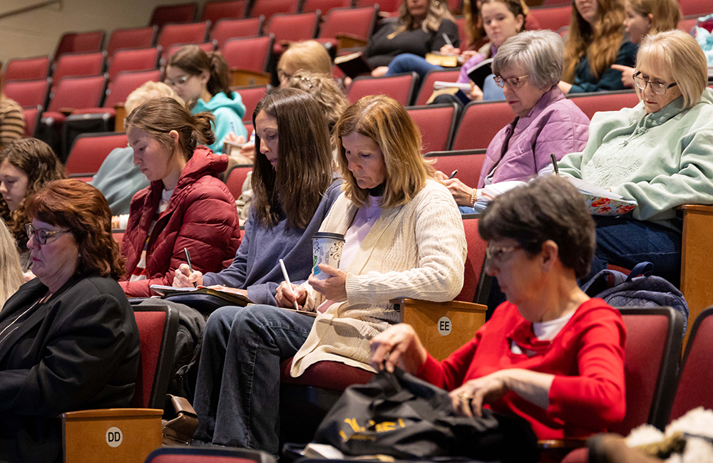 Women in the crowd taking notes during one of the women's sessions of the FHU Spiritual Growth Workshop